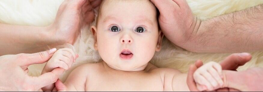 bebe con manos de padre y madre alrededor