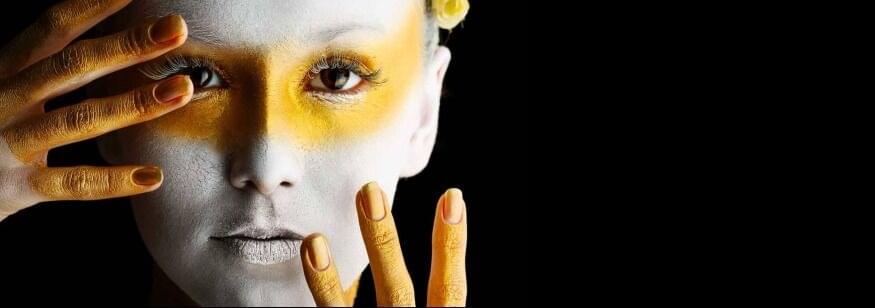 cara y manos de mujer pintadas de blanco y amarillo